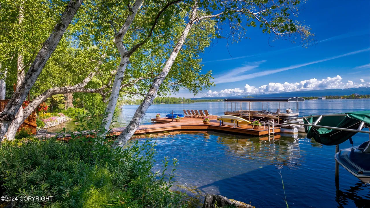 Dock with pontoon boat and kayak under summer sky