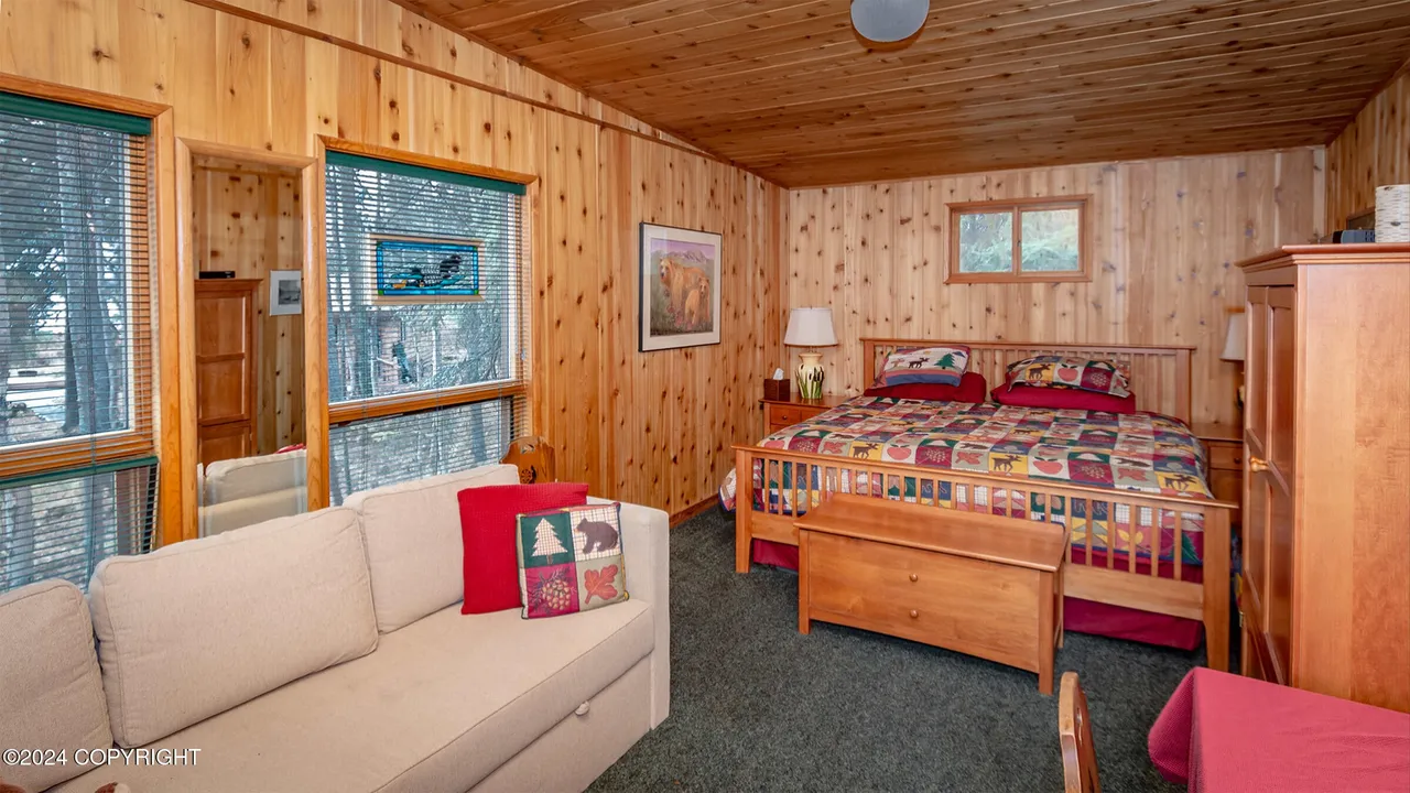 Guest cabin bedroom with quilted bed and reading sofa